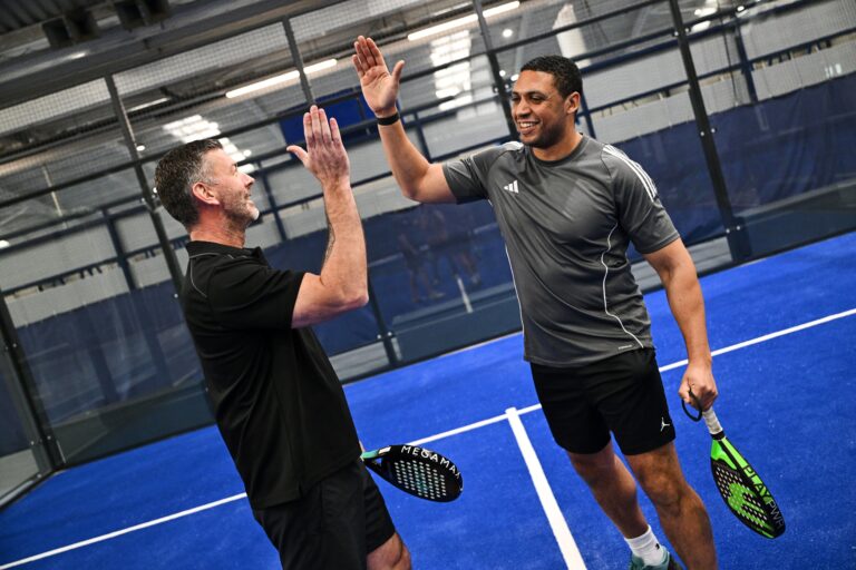 Two people playing tennis high fiving
