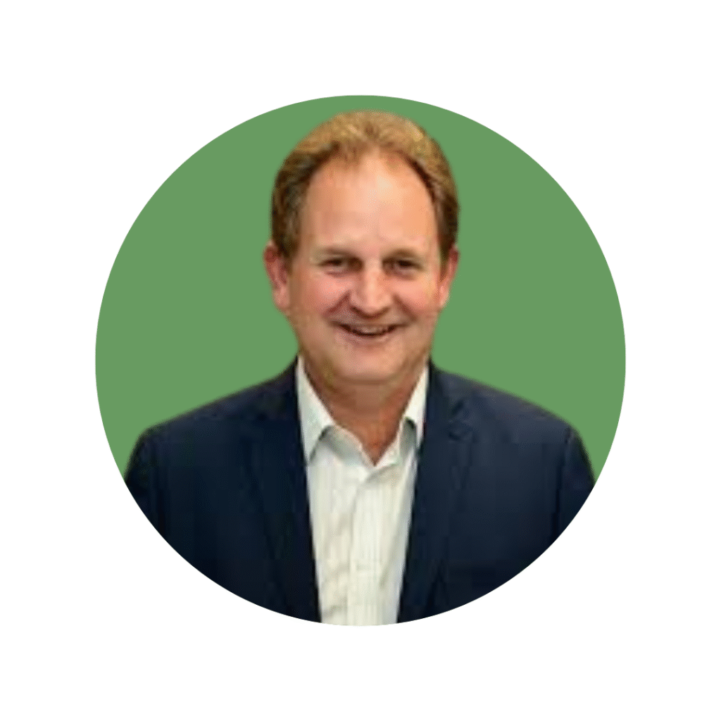 Man with brown hair, shirt and suit jacket smiling at camera
