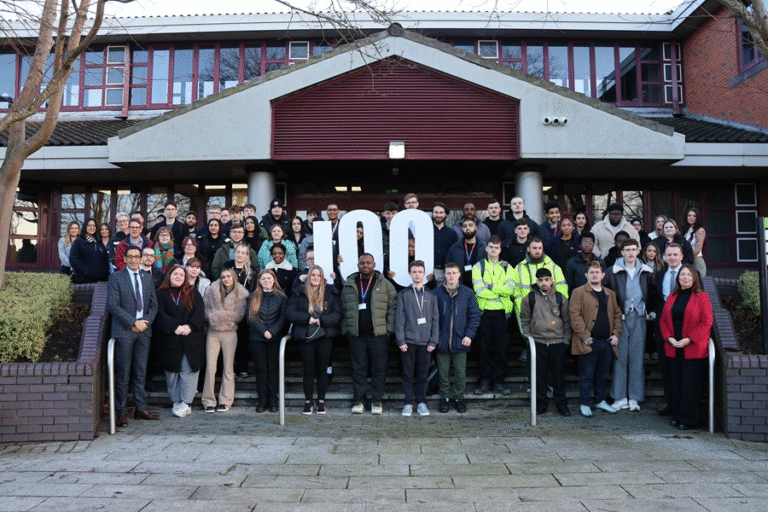 a group of apprentices are stood on the steps outside of Sandwell Council House. The second row are holding up numbers in white which show '100'