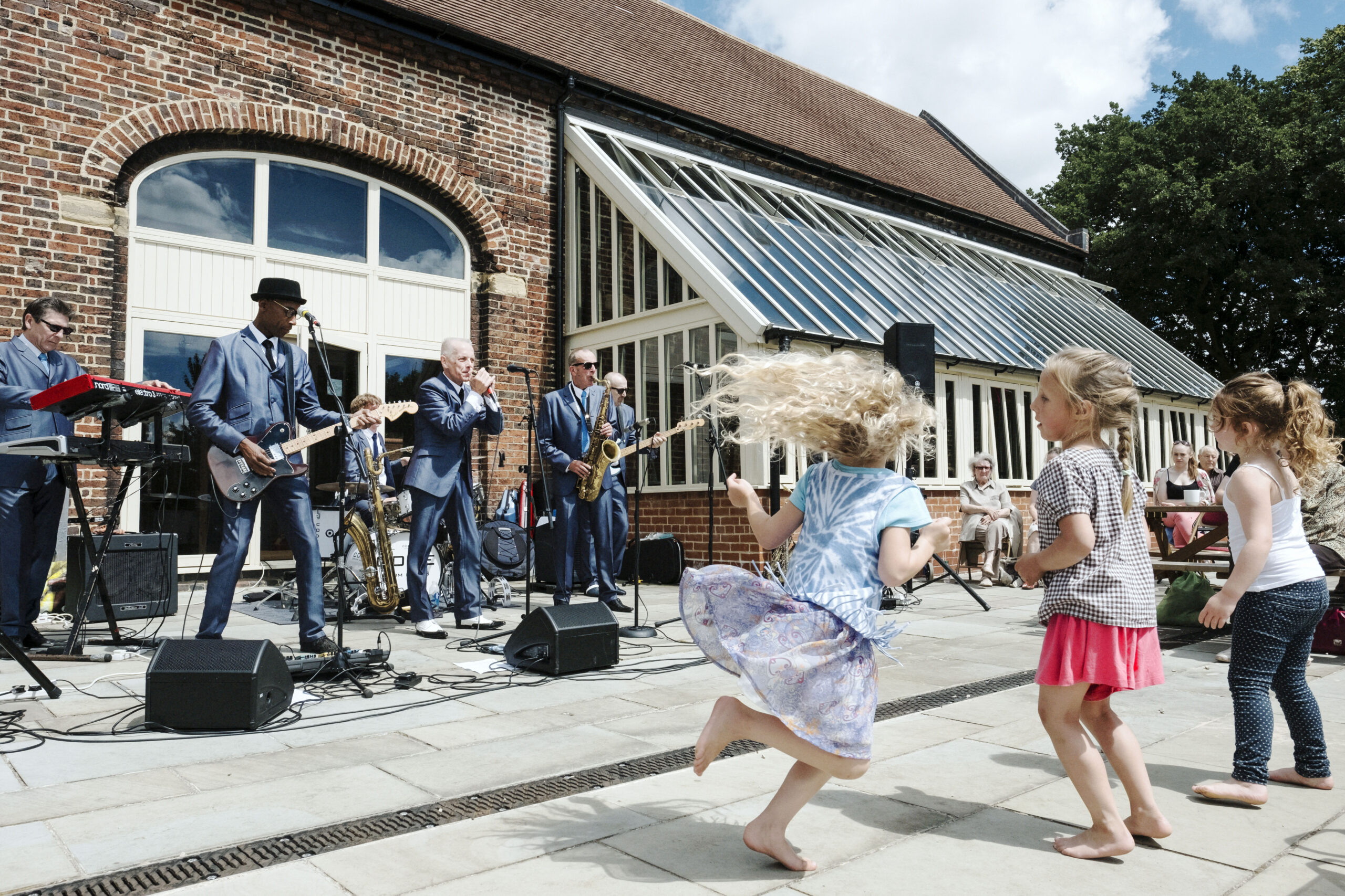 three children dance in summer clothing in front of a jazz band at Oak House Museum