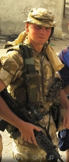 Karl Hinett aged 18 in Army uniform - hat and jacket, in Basra, Iraq in front of stone building